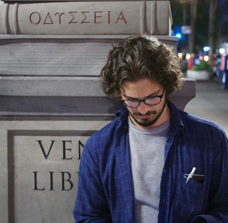 A picture of a pensive man with Powell's Books stone column in the background.